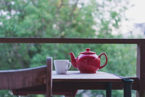 Tea table with red teapot and white mug on balcony