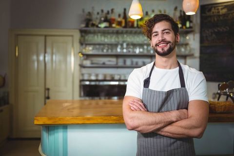 Smiling Young Bartender in Café with Crossed Arms