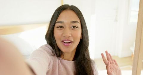 Young Asian Woman Videocalling in Cozy Bedroom Setting