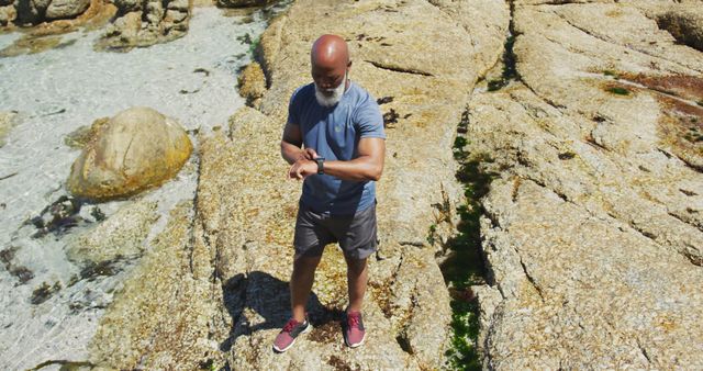 Active Senior Man Exploring Rocky Coastal Terrain and Checking Fitness Watch - Download Free Stock Images Pikwizard.com