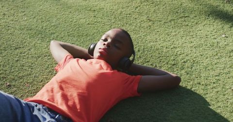Young Boy Relaxing on Grass with Headphones Enjoying Music