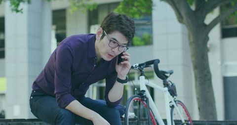 Asian Commuter Calling by Bicycle in Urban Office Plaza