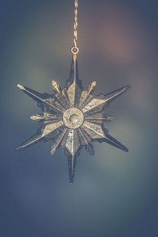 Vintage silver star ornament hanging against blurred background