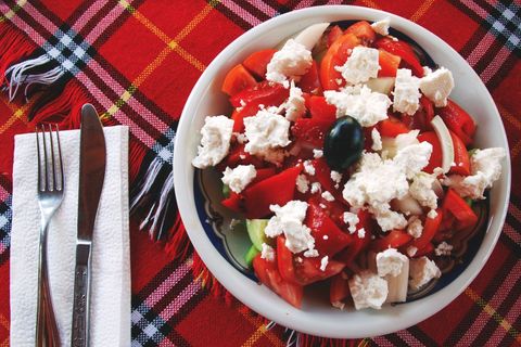 Mediterranean tomato feta salad with olive on red plaid tablecloth top down fork knife