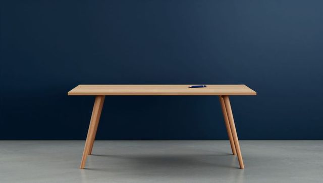 Displaying minimalist light wood table with dark blue pen against deep blue wall