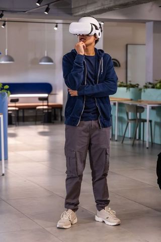 Asian man exploring virtual reality in coworking lounge wearing white vr headset