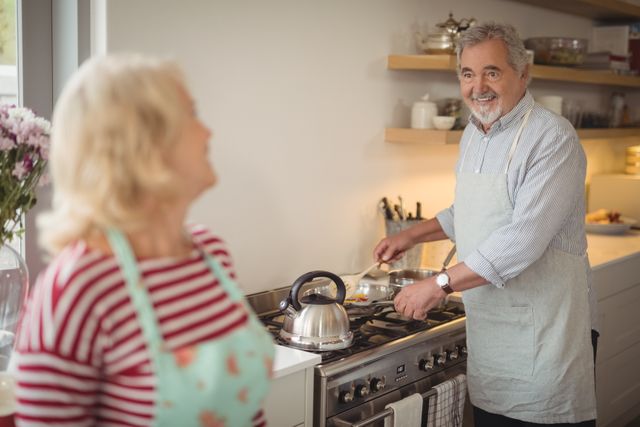 Smiling senior couple preparing food while interacting in kitchen at home
