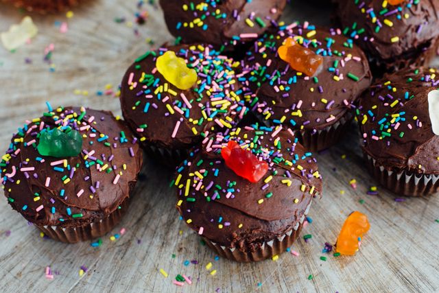 This image shows a group of delicious chocolate cupcakes decorated with colorful sprinkles and topped with gummy bears, making them fun and appealing for parties, birthdays, or any celebratory gatherings. These cupcakes can be used for promoting bakeries, dessert recipes, or festive occasions. They are perfect for use in advertising confectionery products, blogging about baking, or social media posts celebrating special events.