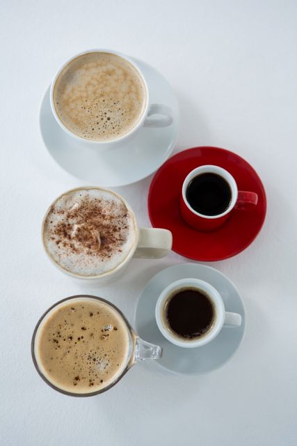 Top view of different types of coffee in cups arranged on white background