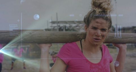 Determined female athlete carrying log through muddy obstacle course with hud graphics