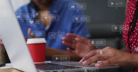 Collaborating and typing on laptop with coffee and social media notification overlays, team