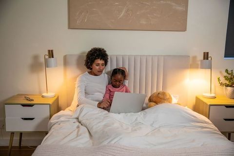 Mother and Daughter Relaxing on Bed With Laptop