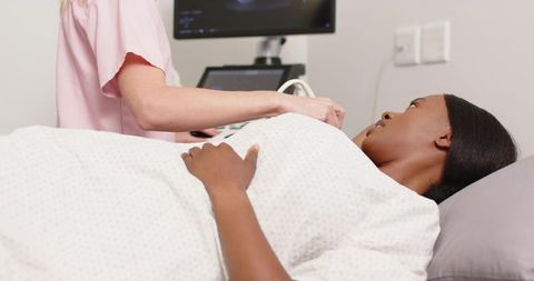 Expectant woman undergoing prenatal ultrasound with clinician in clinic