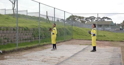 Female softball players in bullpen preparing for practice