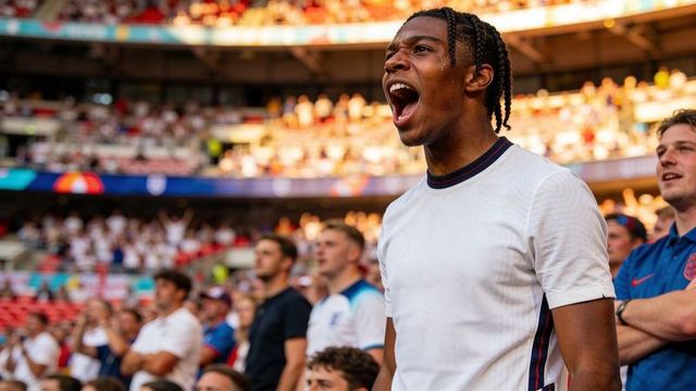 Shouting fan with braided hair cheering passionately at football stadium crowd