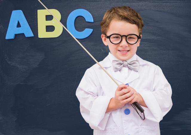 Young boy dressed as a teacher standing in front of a blackboard, holding a pointer and wearing glasses and a bow tie. Ideal for educational materials, school promotions, playful learning concepts, and advertisements targeting parents and educators.
