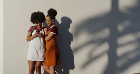 Happy Twins Enjoying Smartphone Outdoors