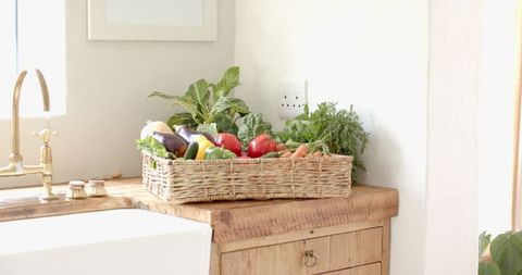Wicker basket with fresh vegetables on rustic kitchen counter