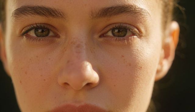 Gazing teen with freckles and hazel eyes during golden hour close-up portrait, sunlit skin