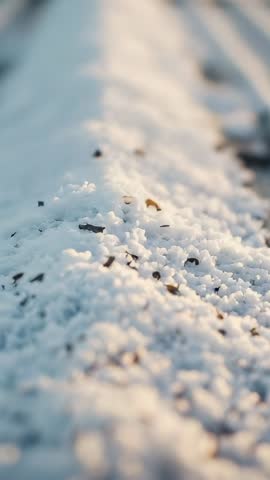Vertical 4K footage panning along graupel ridge on roadside at golden hour, closeup bokeh