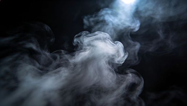 Billowing white smoke plume flowing across black background cool blue accent lighting