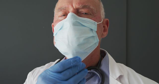 Senior healthcare professional wearing medical face mask and gloves, showing protective measures against viruses. Useful for content on health and safety, medical guidelines, senior healthcare, and hospital environments.