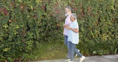 Senior Couple Walking on Sidewalk with Coffee Cups