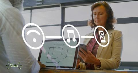 Mature businesswoman checking smartphone while collaborating with team in modern office
