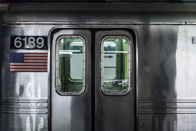 This close-up captures gleaming, metallic doors of a subway train, showcasing public transit in an urban American city. The identifying number '6189' and an American flag are present on the train, denoting its country. This image is ideal for content related to urban commuting, public transportation systems, city life, and travel guides.