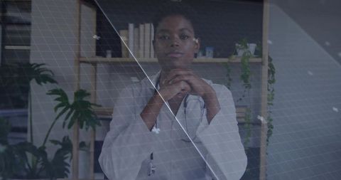 Doctor sitting at modern office desk under technology overlay