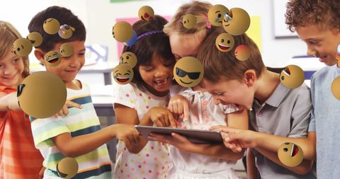 Diverse children engaging with digital tablet and emoticons in classroom