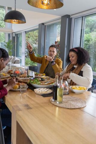 Diverse friends sharing cozy modern dinner around wooden dining table