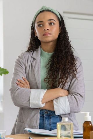 Confident african american woman standing with arms crossed in minimalist home office