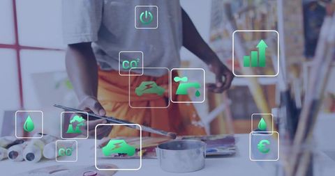 Male artist mixing paints wearing orange apron with green sustainability icons overlay