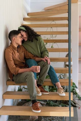 Young couple sharing cozy morning moment on modern floating wooden stairs at home