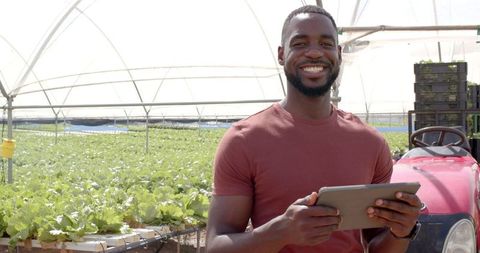 Smiling farmer using a digital tablet to manage hydroponic crops