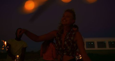 Joyful summer beach party with friends holding sparklers