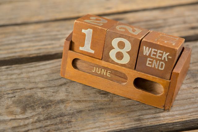 Wooden calendar showing June 18 and weekend on a rustic wooden table. Ideal for illustrating concepts of time, date, and vintage decor. Perfect for blogs, articles, and social media posts about time management, weekend plans, and rustic home decor.