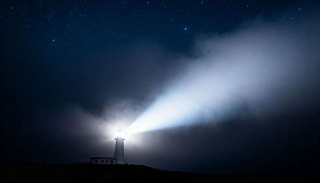 Lighthouse beam cutting through fog at night under starry sky, coastal beacon