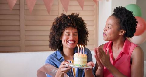 Happy Female Couple Celebrating Birthday at Home with Cake