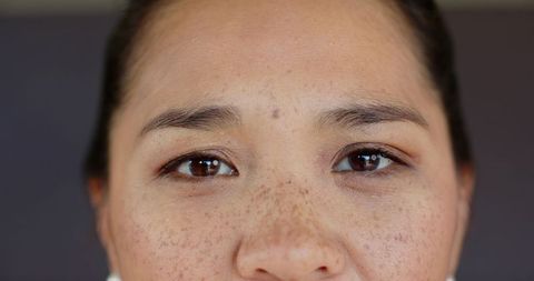 Close-up portrait of asian woman with freckles and stud earrings