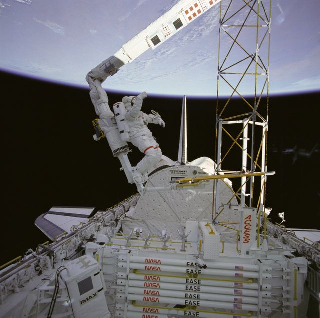 NASA astronaut conducting a spacewalk during the STS-61B mission, working on the ACCESS structure from the Space Shuttle Atlantis. Ideal for topics on space exploration, NASA missions, mechanical engineering studies, and advancements in space technology.