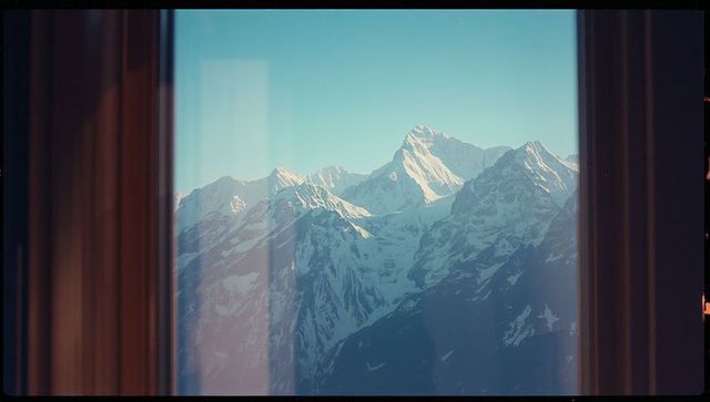 Snow-Covered Peaks Framed by Window Reflecting Morning Light
