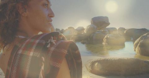 Woman Relaxing at Rocky Seaside Draping Plaid Blanket