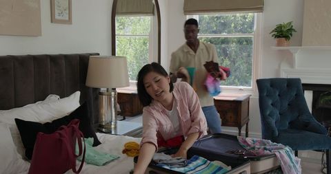 Couple Preparing for Vacation Packing Suitcase in Bedroom
