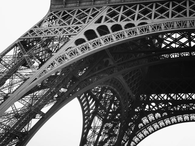 Detailed view of the intricate ironwork of the Eiffel Tower showcasing its engineering marvel. Ideal for use in articles about travel, architecture, and Paris landmarks. This stock photo emphasizes the detailed craftsmanship and design of this world-renowned structure, suitable for educational content, historical articles, and decorative posters.
