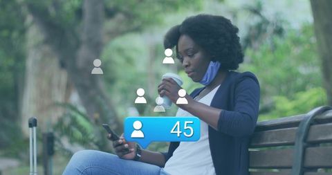 Young black woman scrolling smartphone on park bench holding coffee with follower notification 45