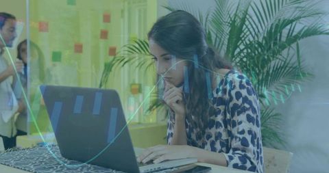 Focused woman analyzing data on laptop in modern coworking space with analytics overlay