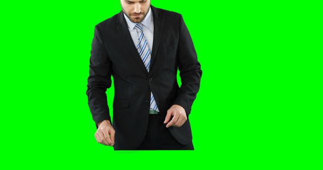 A Caucasian businessman is adjusting his suit jacket, with copy space on the green background. His professional attire and action suggest he is preparing for an important meeting or event.