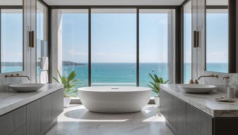 Freestanding tub overlooking turquoise ocean through panoramic glass in luxury bathroom